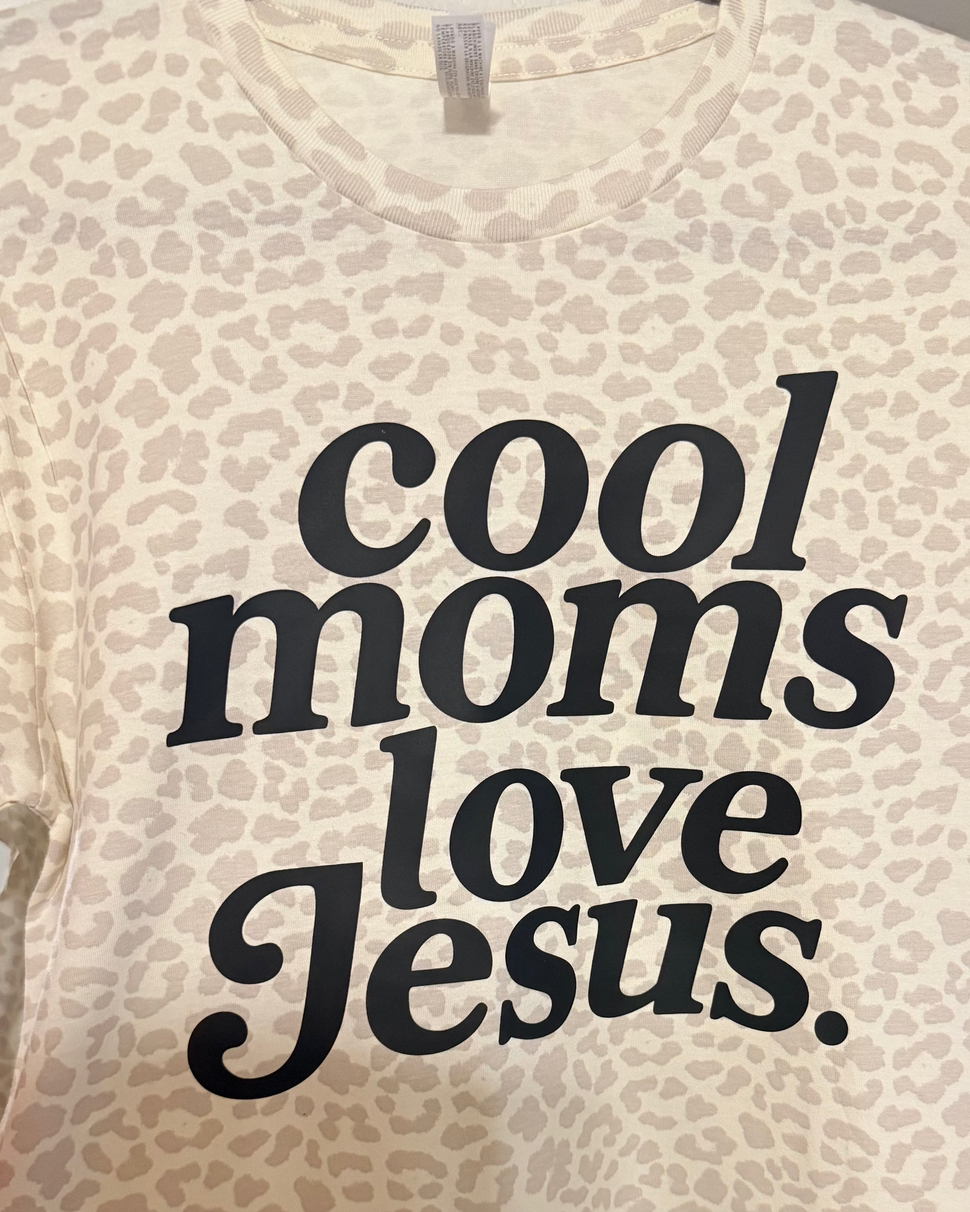 T-shirt with 'cool moms love Jesus' text on a beige background